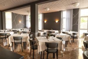 a restaurant with white tables and chairs and windows at Hotel Al Molino in Malcesine