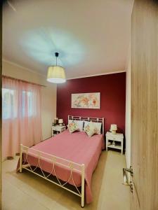 a bedroom with a bed with a red wall at Μάζης Εξοχικές Κατοικίες in Dhiyeliótika