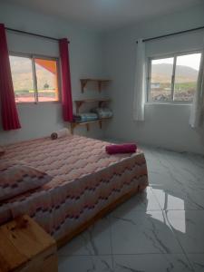 a bedroom with a bed and two windows at Casa Pirinha in Portela