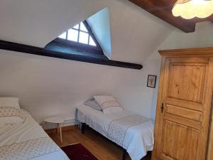 a attic bedroom with two beds and a window at Escapade bucolique calme et nature in Saint-Léger-aux-Bois