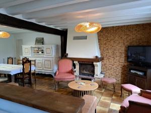 a living room with a fireplace and pink chairs at Escapade bucolique calme et nature in Saint-Léger-aux-Bois