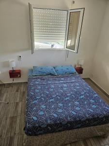 a bedroom with a bed with a blue comforter and a window at Kaz a kann là in Petit-Canal