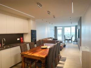a kitchen and living room with a wooden table and chairs at Art Donna met zeezicht in Middelkerke