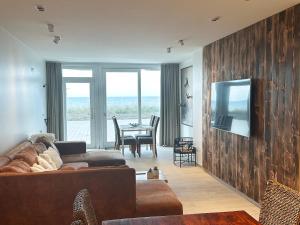 a living room with a couch and a television on a wall at Art Donna met zeezicht in Middelkerke