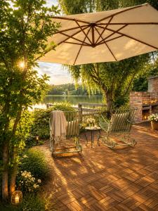 a patio with two chairs and a table and an umbrella at Das Seehaus Buckow in Buckow
