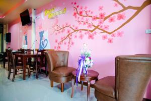 a dining room with a pink wall with a tree mural at Sweet Dreams Hometel in Krabi town