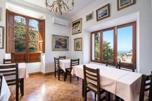 a dining room with tables and chairs and windows at Hostal Miramar in Deia
