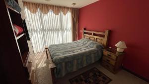 a bedroom with a bed and a red wall at Muy cerca, a pasos de la Embajada de EEUU in La Paz