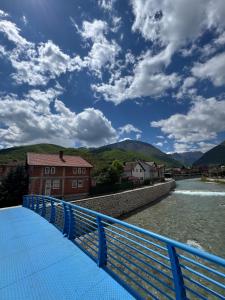 a blue bridge over a river with mountains in the background at Peja Riverside Hostel in Peje