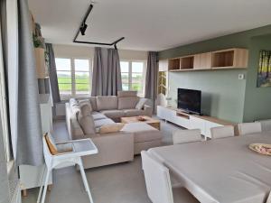 a living room with a couch and a tv at 't Ooievaarszicht in Veurne