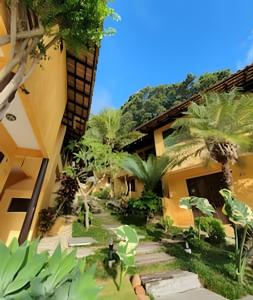 a building with a courtyard with palm trees at Villa Garoupeta in Bombinhas