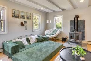 a living room with a green couch and a fireplace at Tranquil Catskills Home w/ Creek & Fire Pits in Parksville