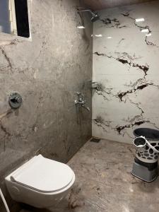 a bathroom with a toilet and a marble wall at Velkar Cottage Mahabaleshwar in Mahabaleshwar
