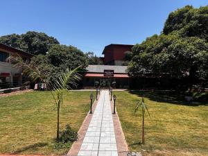 a walkway in front of a building in a field at Velkar Cottage Mahabaleshwar in Mahabaleshwar
