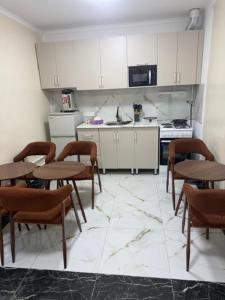 a kitchen with wooden tables and chairs in a kitchen at Bayan hostel in Osh