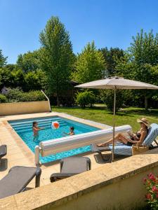 a group of people in a swimming pool with an umbrella at Les Chalets du Brusquand in Marquay