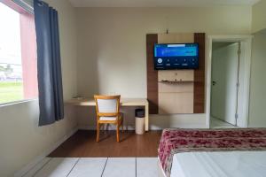 a room with a bed and a chair and a television at Nobile Hotel Belém in Belém