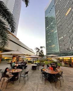 a group of people sitting at tables in front of buildings at Heron Marinho Comfort Flat in Campina Grande