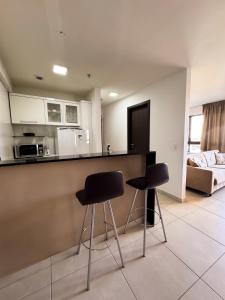 a kitchen with two black stools in a room at Heron Marinho Comfort Flat in Campina Grande