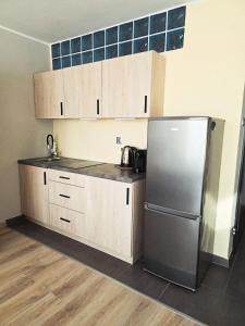 a kitchen with a stainless steel refrigerator and cabinets at Dominikana Apartament 41b in Sianozety