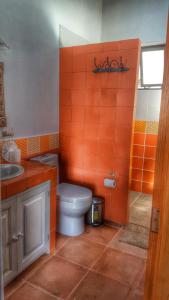 baño de color naranja con aseo y lavamanos en El Macehual, en San Miguel de Allende