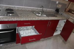 a kitchen counter with red cabinets and a sink at Résidence La Place in Laayoune +27 photos