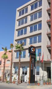 a parking meter in front of a building with palm trees at Résidence La Place in Laayoune