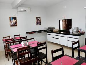 a dining room with pink tables and a kitchen at Fênix Hotel Colinas do Tocantins in Colinas do Tocantins