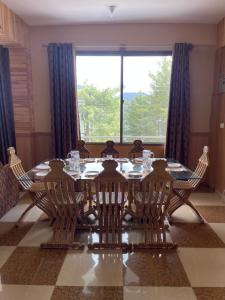 a dining room table with chairs and a large window at Hillside Cottages, Kala Bagh in Nathia Gali