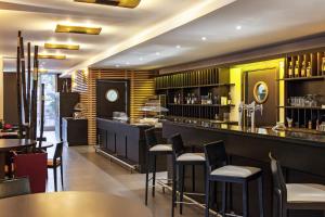 a restaurant with a bar with tables and chairs at Ibis Barcelona Molins de Rei in Molins de Rei