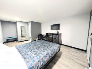 a hotel room with a bed and a flat screen tv at BlissPoint Inn Muncie in Muncie