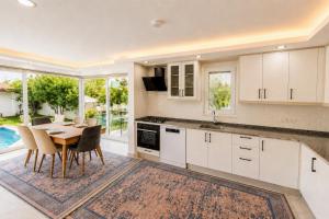 a kitchen with white cabinets and a table with chairs at Villa Sena in Dalyan