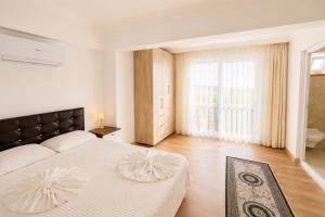 a white bedroom with a large bed and a large window at Villa Sena in Dalyan