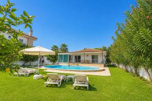 a backyard with a pool and chairs and a house at Villa Sena in Dalyan