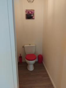 a bathroom with a toilet with a red lid at Chambre in Château-Garnier
