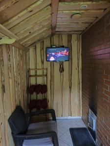 a room with a tv and a couch and a brick wall at Katase Guest House in Katase