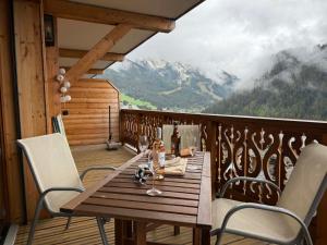 a wooden table and chairs on a balcony with a view at Perle de Savoie Free multipass offer for 4 guests in Châtel