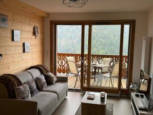 a living room with a couch and a balcony at Perle de Savoie Free multipass offer for 4 guests in Châtel