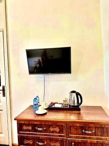 a flat screen tv on a wall with a wooden dresser at Officers Boutique Hotel in Samarkand