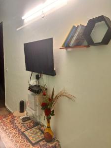 a flat screen tv sitting on a wall with a vase at Varāya 1RK Studio in Vrindāvan
