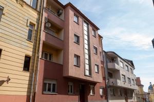 a red building with white windows on a street at AApartman Prime in Pécs