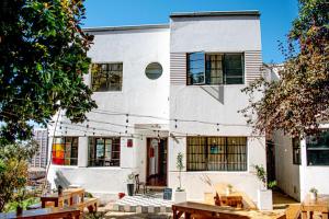 a white building with tables in front of it at Hostel Hotzenplotz Alegre in Valparaíso