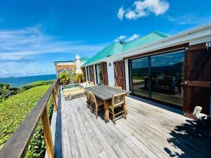 a wooden deck with a table and a view of the ocean at Case Macalpa in Saint Barthelemy