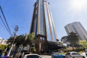 a tall building with cars parked in front of it at Flat Hotel 4 estrelas próx. Aeroporto GRU até 6p in Vila Gopoúva