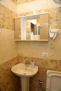 a bathroom with a sink and a mirror and a toilet at Lake Bliss Cabins in Shkodër