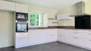 a white kitchen with white cabinets and a window at Gîte de la Verdière Spa Pool Valley in Le Sourn
