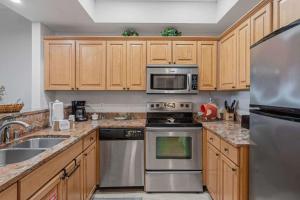 a kitchen with wooden cabinets and stainless steel appliances at Easy Beach Walk Pools and Hot Tubs in Destin