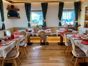 a dining room with tables and chairs with red dishes at Garni al Barance in Selva di Cadore
