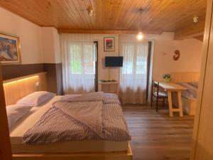 a bedroom with a bed and a desk and a table at Garni al Barance in Selva di Cadore