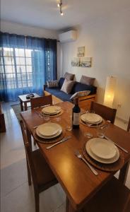 a wooden dining room table with plates and wine glasses at Apartamento Sunrise in Altura +8 photos